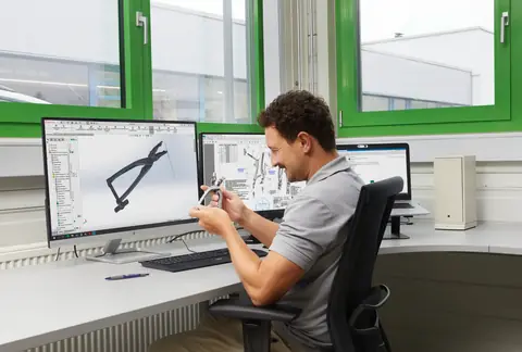 Mitarbeiter prüft ein Instrument neben dem CAD-Modell